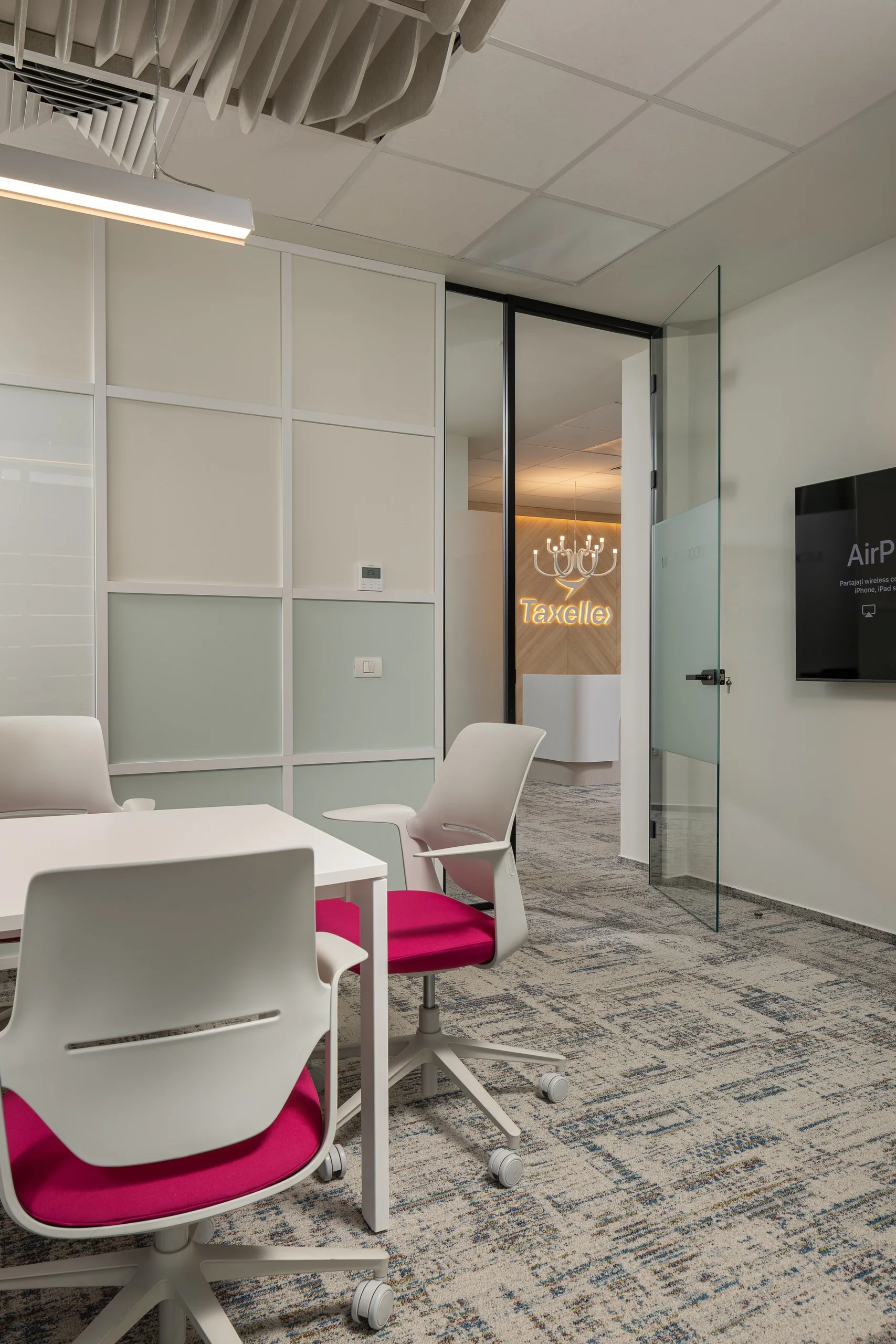 Taxelle - spațiul de lucru cu scaune magenta și pereții de sticlă spre recepție